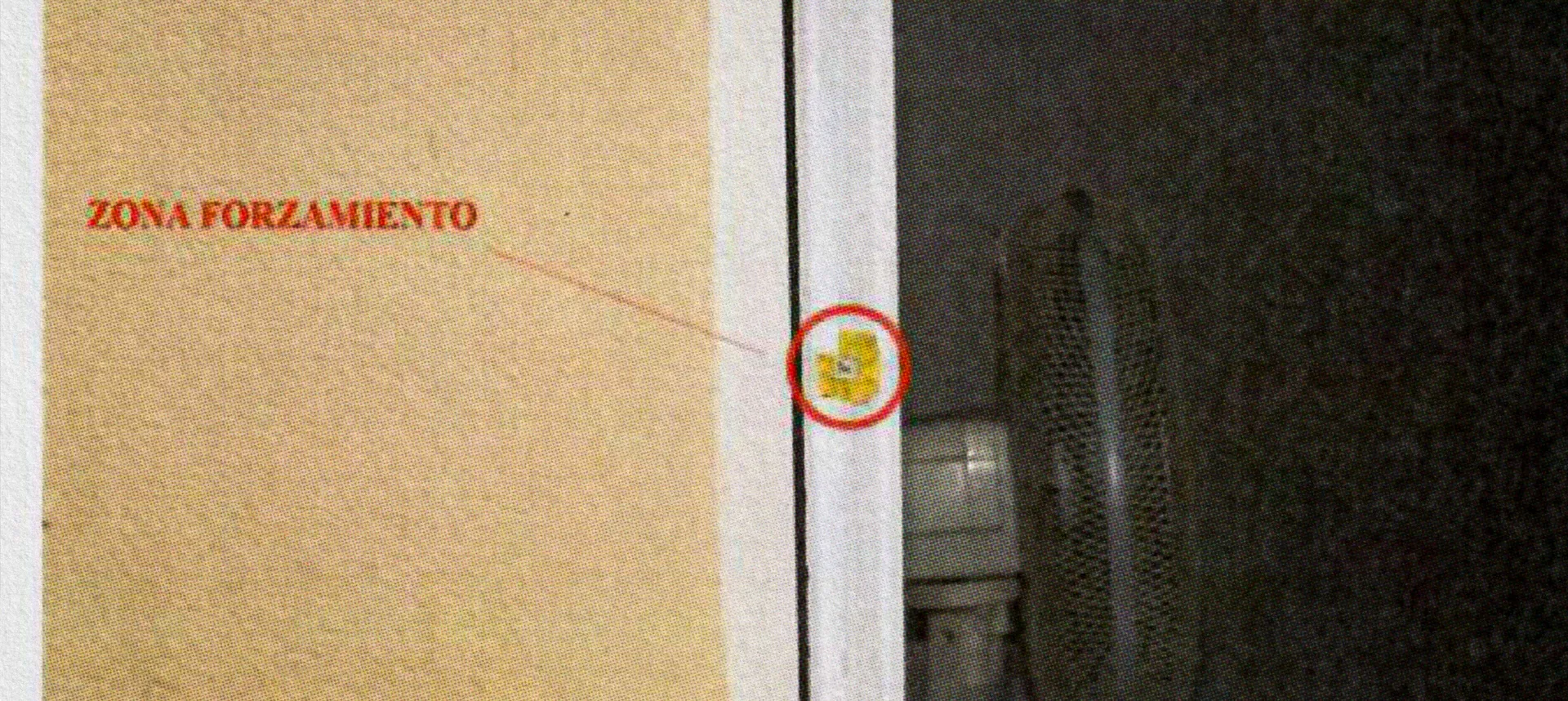 Imagen de la serie: fotografía de una puerta con un círculo rojo sobre la cerradura y el rótulo «Zona forzamiento»