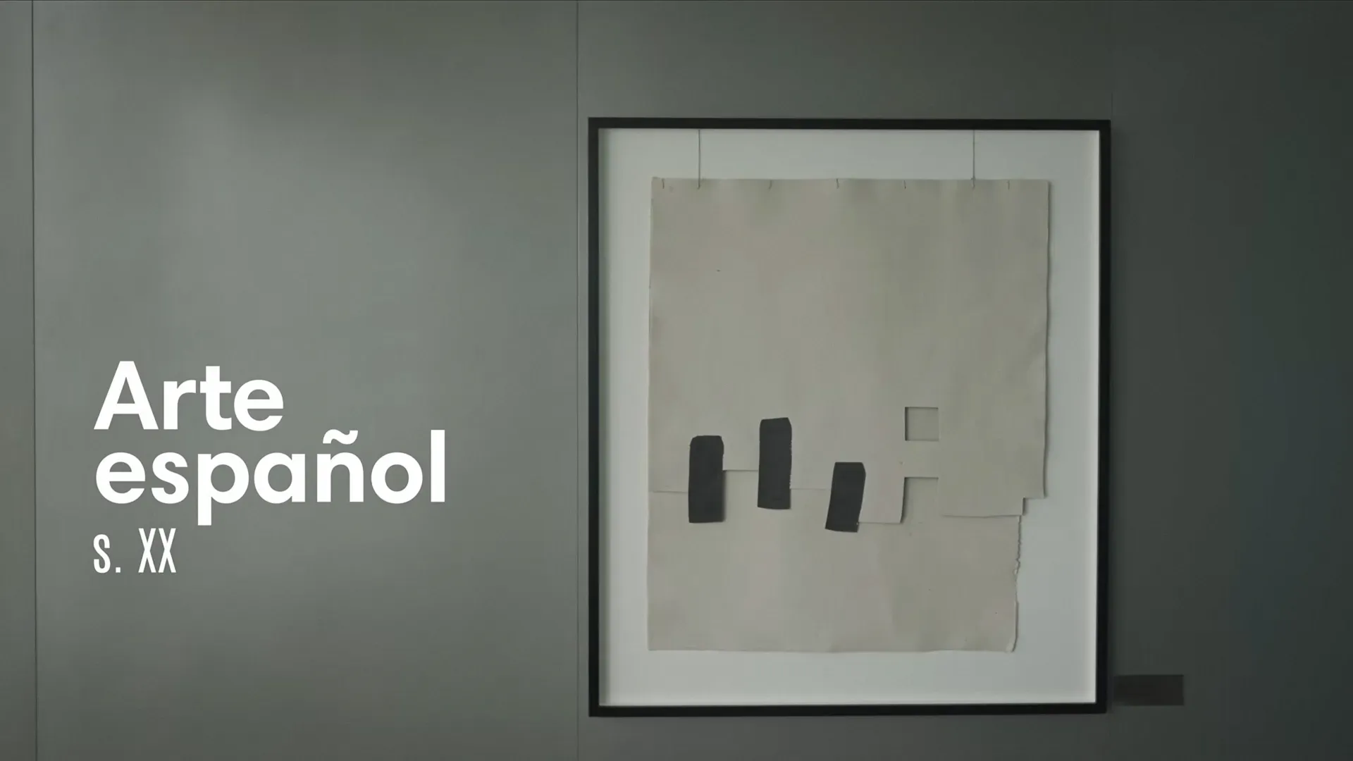 Fotograma del vídeo: una obra abstracta de papel gris con tres formas negras, enmarcada en una pared gris, y a la izquierda el rótulo «Arte español s. XX»